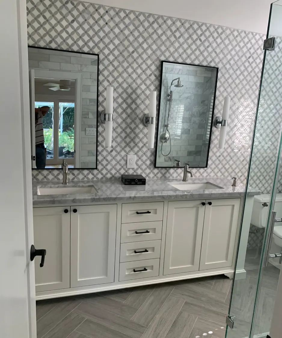 Double vanity with marble counter and patterned tile wall