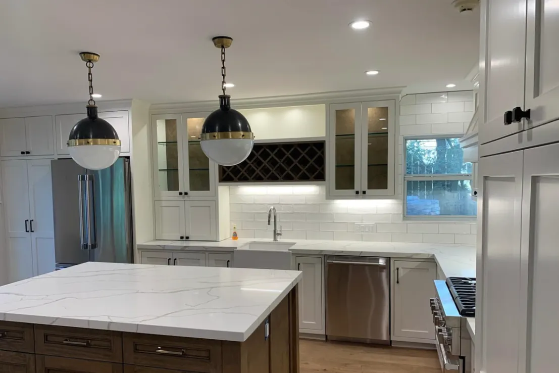 Remodeled white kitchen with quartz island and globe pendants